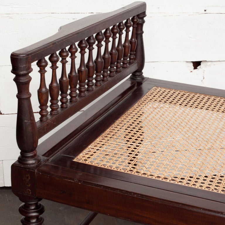 Anglo-Indian solid rosewood daybed with spindle turned head and footboard. Eight turned legs have brass caps and square profile bottom rails.