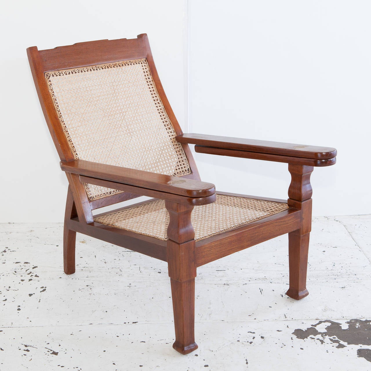 Teak plantation chair from India with folding arms and newly caned seat.