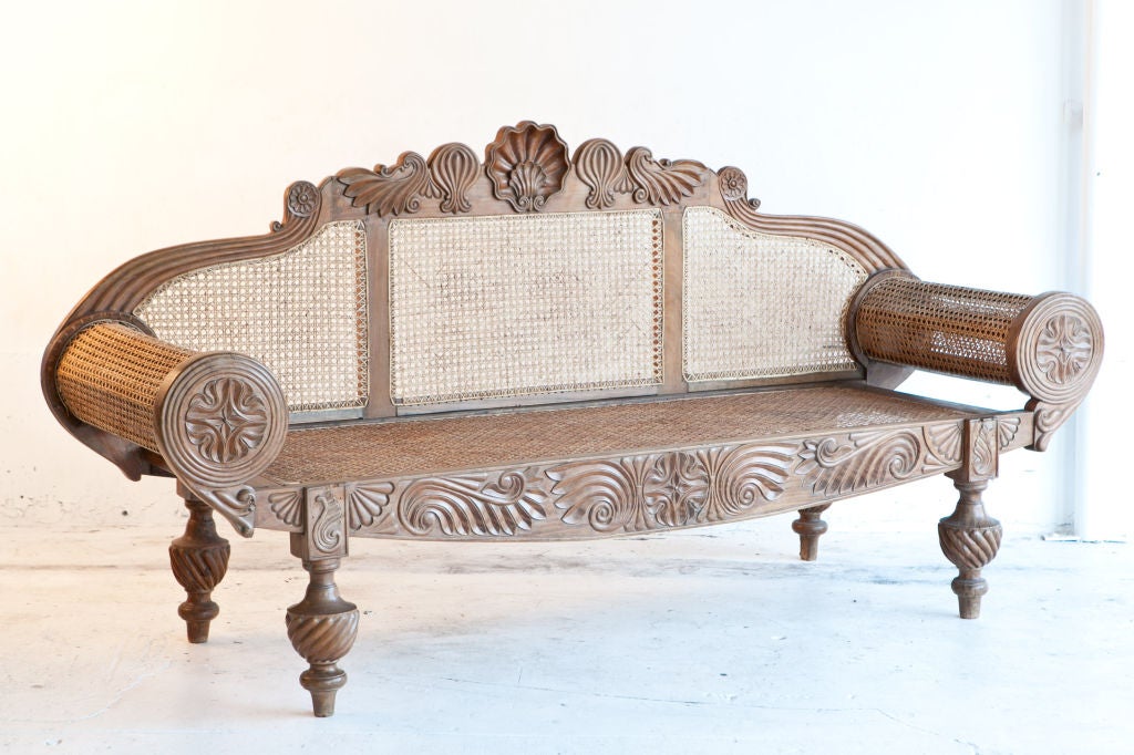 Dutch colonial settee made of rare nadun wood an extremely dense even grained, tropical hardwood. All major surfaces are carved. Overall nicely proportioned settee with caned seat, back and cylindrical arms.