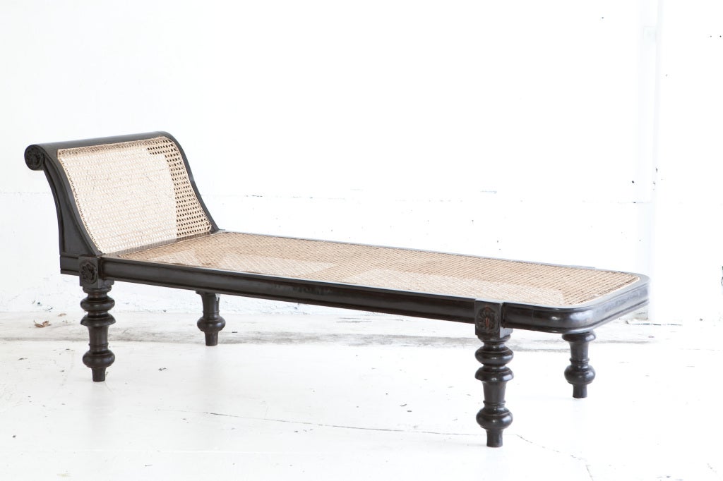 A reproduction of an Anglo-Indian solid ebony daybed, side rails have a convex carved pattern which wraps around the entire frame. The wood is antique ebony used to create the reproduction. The slanted back also has the same convex carving. Seat and