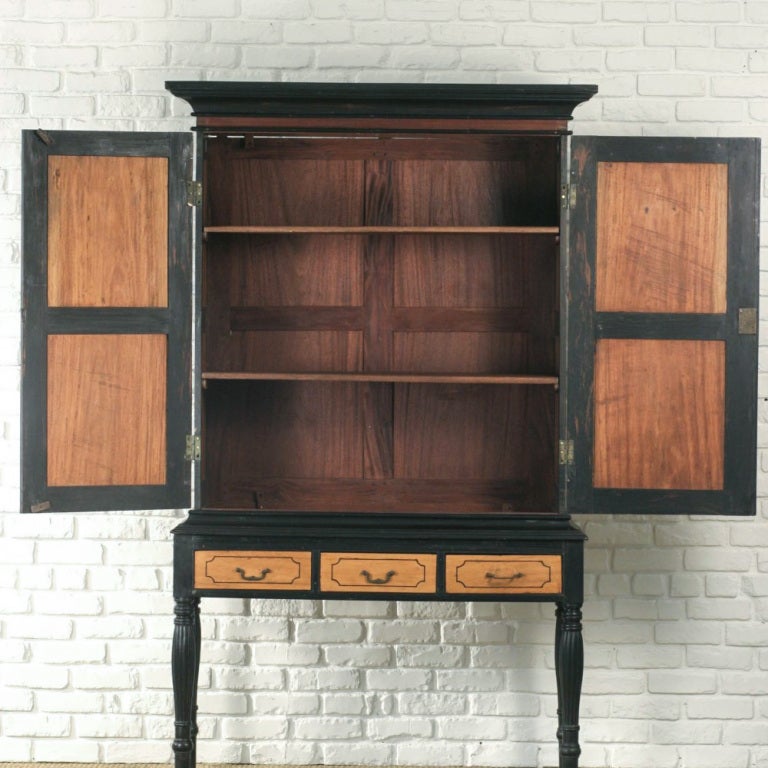 Very rare and unique Indo-Dutch solid satinwood and ebony cabinet on four turned legs. All black details such as large crown molding, door frames and legs are solid ebony. The top cabinet was designed to be collapsible for easy transport. Side