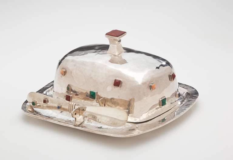 The butter dish with knife is by contemporary Mexican silversmith and designer, Emilia Castillo.  It is highlighted by hand hammering and is studded with pyramid cut semi precious stones including malachite, lapis, carnelian and banded agate.  It is