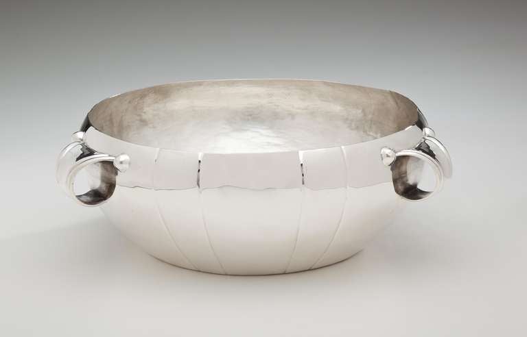 A sterling silver salad or  fruit bowl by William Spratling (1900 - 1967).  The bowl has deep, vertical incised decoration and three strap handles.  The interior shows the hand hammering of the artisan.  Signed with the conjoined WS in a circle,and