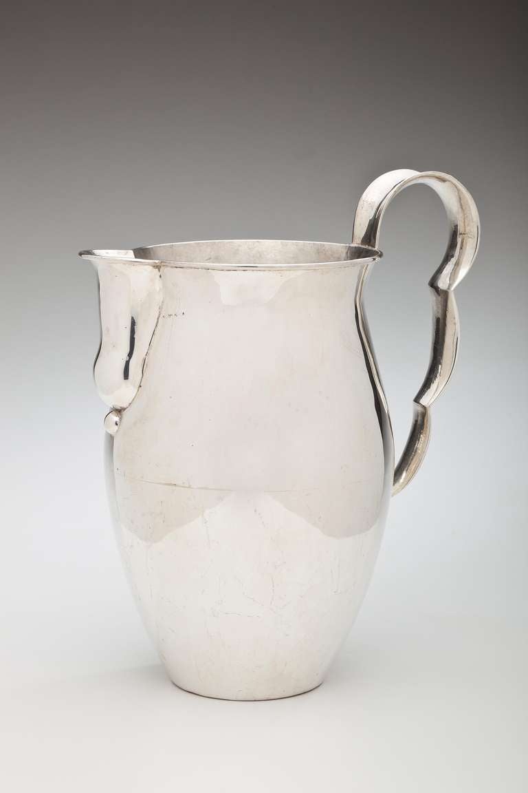 A sterling silver wine pitcher by William Spratling (1900 - 1967)  This pitcher, which can also be used for water, is distinguished by its wavy handle and duck bill shaped spout.  It is hallmarked on the bottom with a conjoined WS in a circle and