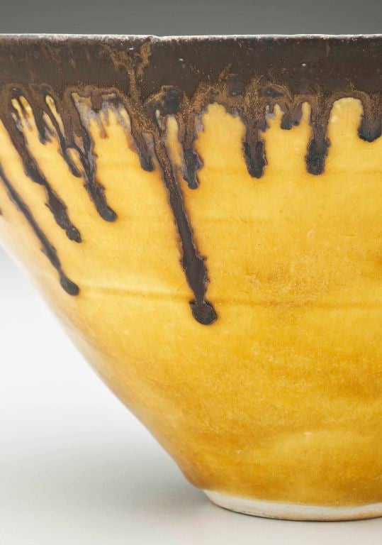 A fine flaring bowl with dripping copper glaze over glossy deep ochre body by Austrian born British potter, Lucie Rie (1902-1995).There is crackling to the glaze which is inherent in the firing.   Impressed with artist's mark.