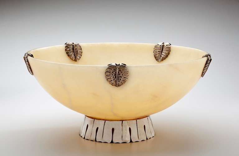 A large alabaster bowl by Emilia Castillo with sterling silver base and decorative accents.  The alabaster bowl is highlighted with five sterling silver leaf decorations spaced around the rim.  The sterling base is scalloped in panels with open