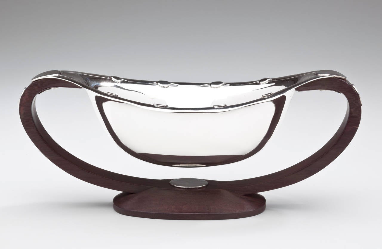 A sterling silver and wood sauceboat by William Spratling (1900-1967). In an innovative design, Spratling created this sauceboat with a flying saucer motif. The oval bowl is accentuated with sterling dots around the scalloped and pierced edges. It