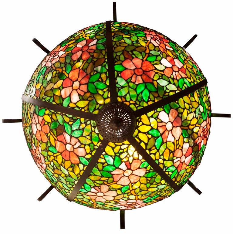 Beautiful large tiffany style glass has been forged in a black iron chandelier. These beautiful colors of rose, peach and green tones make a scrumptious contrast.