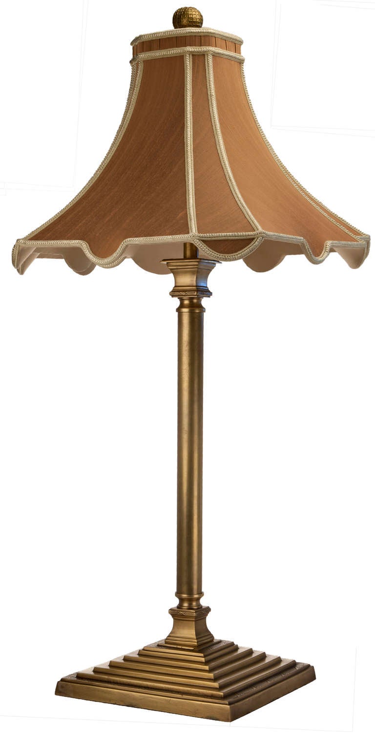 Unusual brass candlestick lamp on stepped pyramid square base with classical x motifs embossed on satin finished brass. Elaborate pagoda shaped silk shade with contrast trim and rouched gallery at top. Round brass finial with x motif overlay.