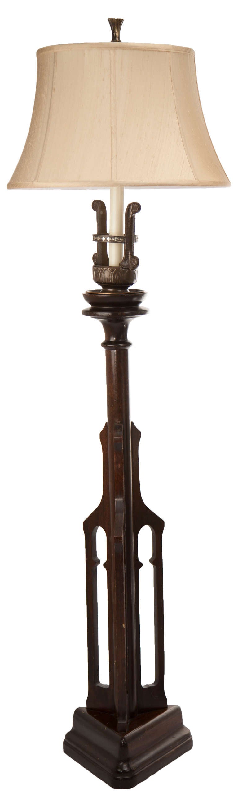 These corpulent floor lamps reflect the somber side of the Art Deco Gothic Revival style. Set upon a weighty tripod base three pierced carved side panels reflect a lancet arch motif.  The mogul sockets are cast bronze and decorated with a quatrefoil