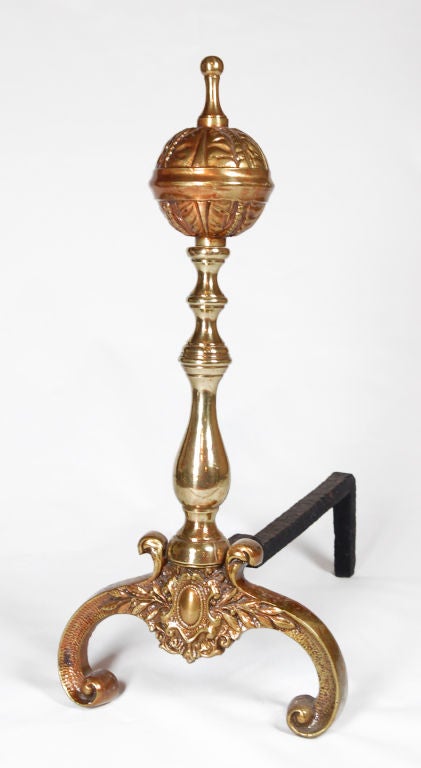 These elegant brass Andirons were created in the style of William and Mary.  They feature turned balusters, ball shaped finals and scroll feet. Cast in wonderful detail with decorative foliage and shield.