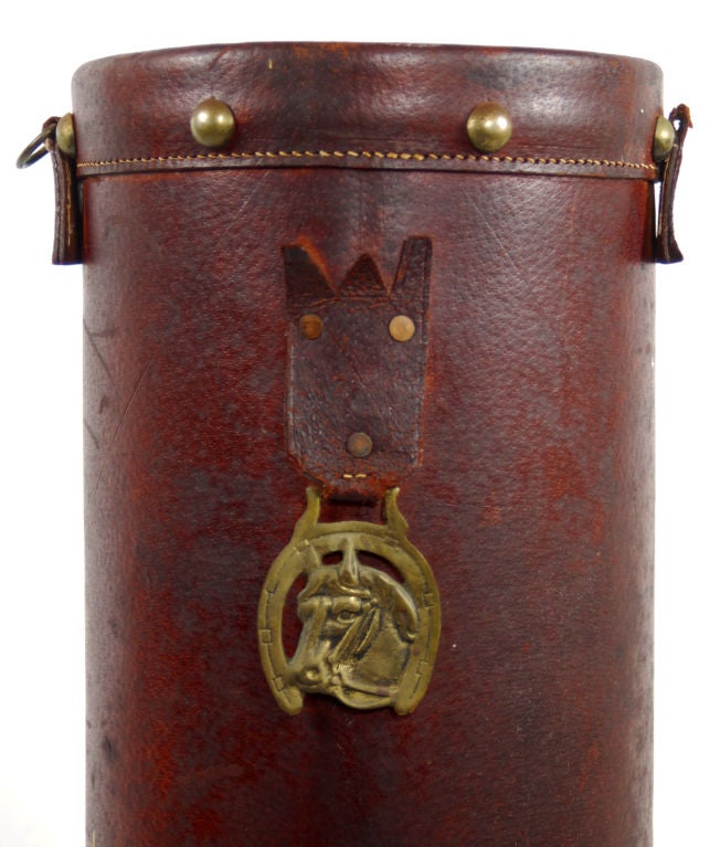 Offering an antique English, leather bucket formerly used in horse stables to ration out oats to horses, or in time of fire, to carry water. This bucket has wonderful hand stitching and large rivets. Classic bronze emblem of horse with horse shoe on