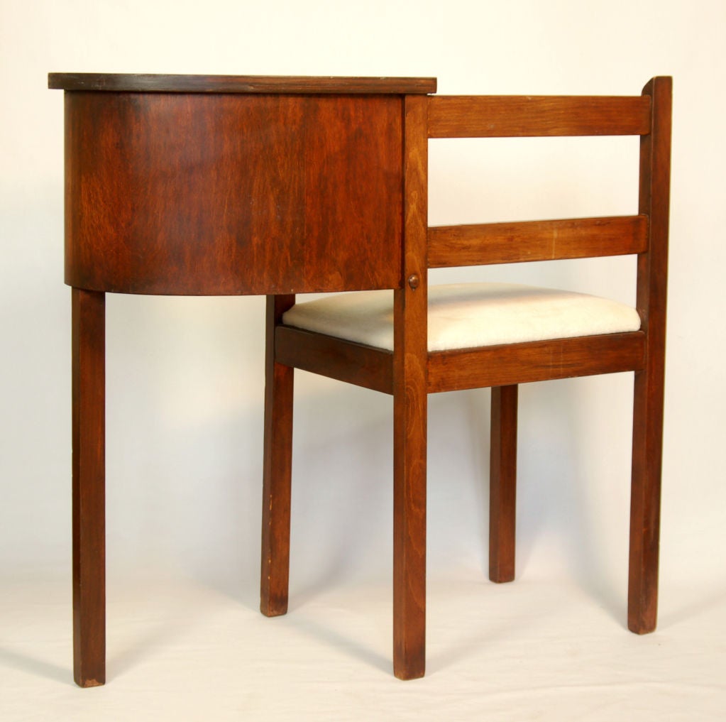 This writing table or telephone has a simple utilitarian form. The form, with its basic linear design, hearkens to Shaker-style furnishings. This functional piece is made out of solid cherry, with storage for writing utensils underneath the pad.