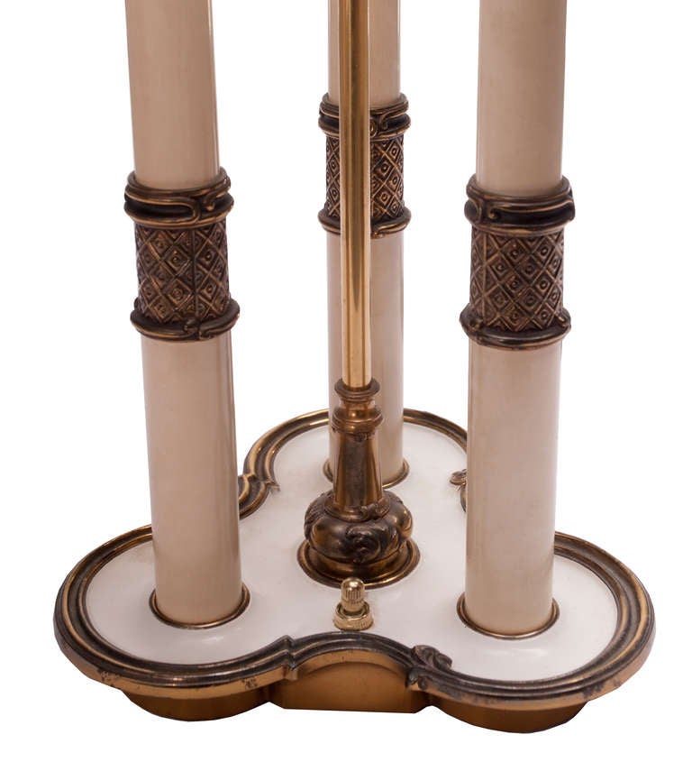 Superbe lampe de table des années 1940, de forme bouillotte avec trois bougies en émail à collier en laiton sur une base trilobée avec un interrupteur sur la base. Abat-jour neuf en soie grège de couleur crème avec grand embout en laiton.