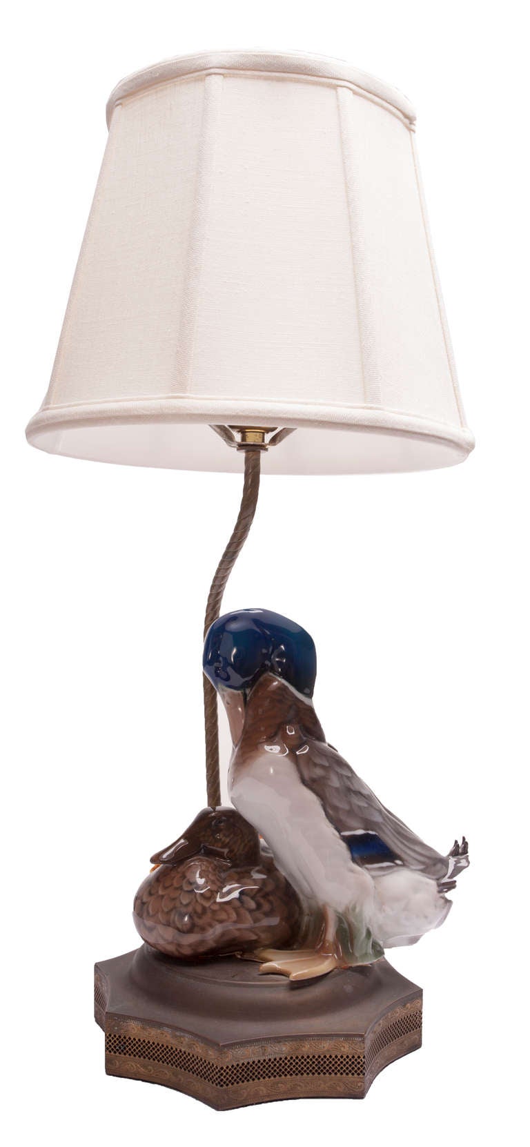 Rosenthal Porzellan Entenpaar, vom Künstler W. Zugel als Lampe montiert, feine filigrane Messingbeschläge auf einem achtseitigen Sternsockel, Seilrohr trägt einen Leinenschirm mit Fayenceknauf. Professionelle Porzellanreparatur an einem