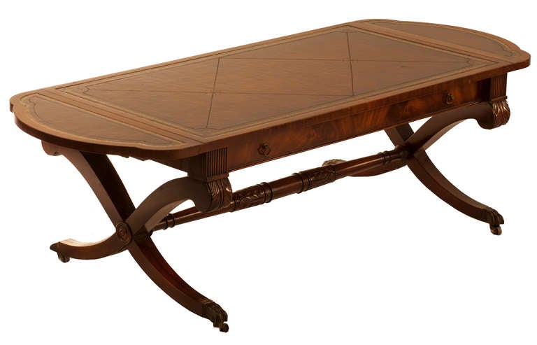 Cocktail Table with drop leaf ends, one wide drawer in apron, egency style x bases with turned stretcher, bronze sabots and casters, gold tooled leather top, marked 