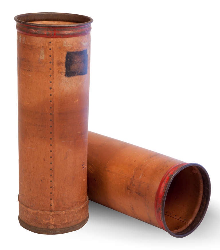 Cylindrical tall containers with metal banding at the top of the leather sides, with red painted bands and black labels.