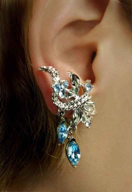 Ice blue rhinestones delicately climb the ear on these fabulous mid century Coro creeper earrings. A luminescent silver tone strand ties this leafy bouquet together as it makes its s-curve ascent up the ear. Piercing yet feminine beauty makes this