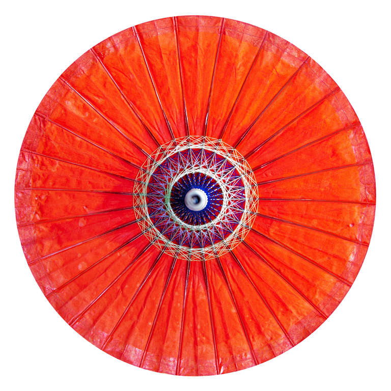 Bright orange parasol from India with black cap and cane stem.
