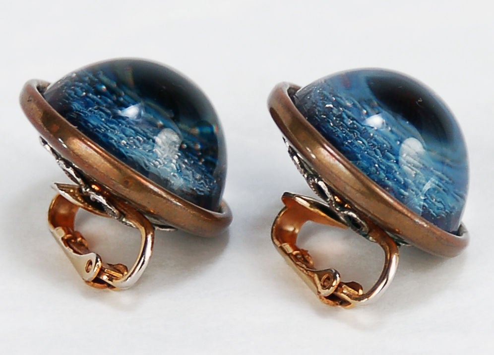 This Atomic age set of clip on earrings feature two large cabochon dichroic glass orbs that have a planetary appearance. Firey oranges and opalescent purples contrast and change colors in the light. These would make a wonderful gift for the space