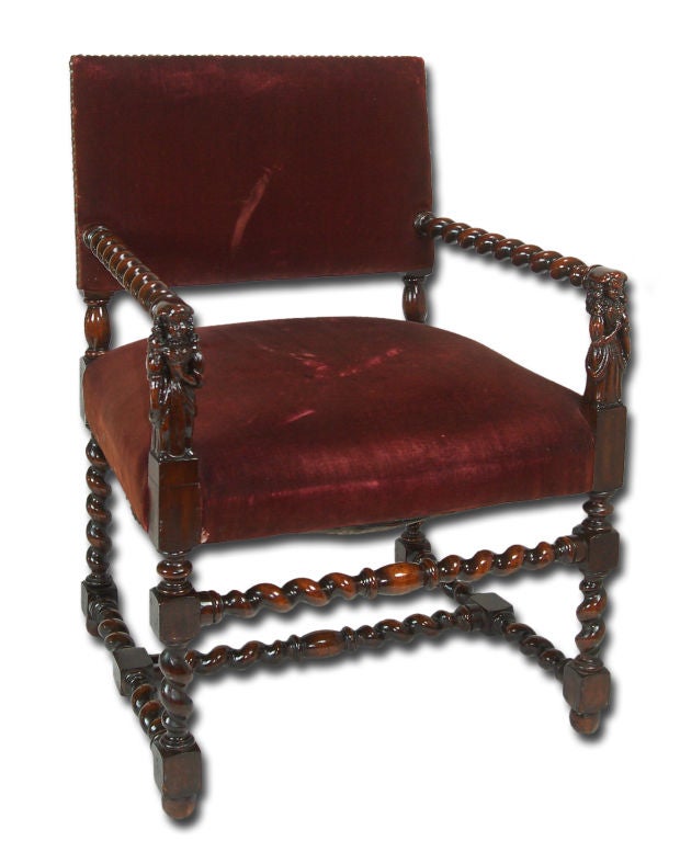 This pair of Jacobean style arm chairs feature spiral turning on the arms, legs and stretchers. The rectilinear form of these chairs is punctuated by rectangular joining blocks. Beautiful hand carved maidens bedeck the arm supports. The velvet