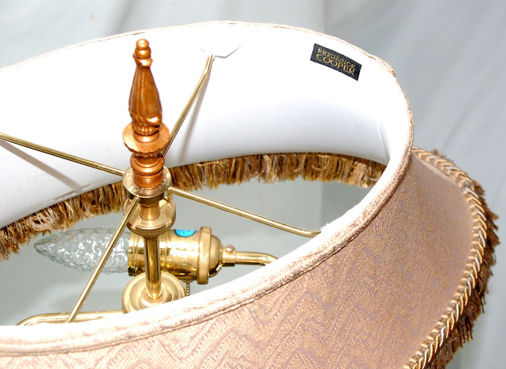 Diese Fackel wurde von Fredrick Cooper entworfen und hat ein klassisches Stehlampendesign. Der gedrechselte Korpus steht auf einem Sockel mit drei Schneckenfüßen. Drei vergoldete Reliefrosetten schmücken den Sockel zusätzlich. Das Ganze besteht aus