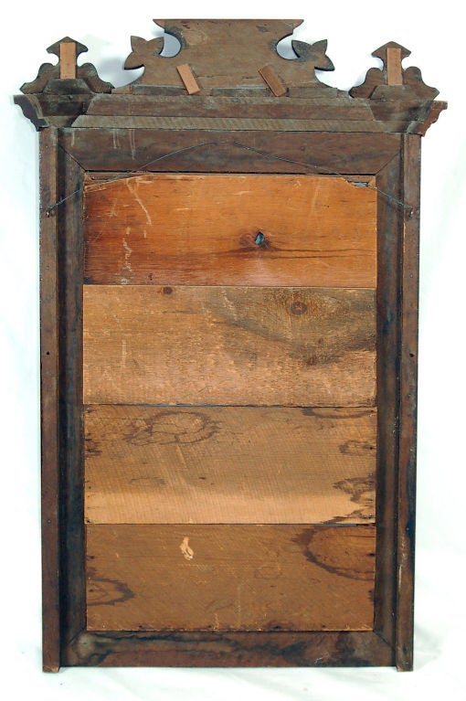 This unique early 20th century American Victorian Renaissance Revival mirror features ornate decoration. The whole is composed of walnut. Black lacquer has been applied to imitate ebony inlay. The corner blocks feature squares bisected on the