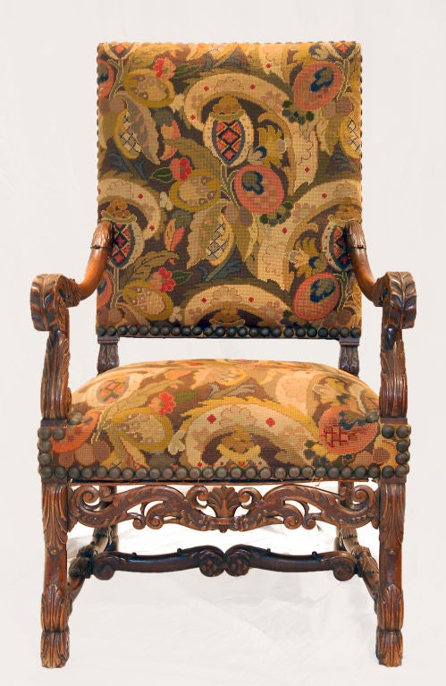 This hand-carved Elizabethan chair has been elaborately decorated. The wooden frame features a carved acanthus leaf motif both on the scrolled arms, legs and cross supports. The apron features a wonderful pierced wood carving replete with scrolls