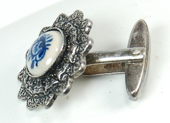 This sweet pair of womens cufflinks features a small delft style porcelain inlay with a hand painted Japanese flower. The silver cufflinks feature an ornate floral motif setting for the porcelain.