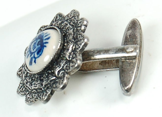 Cette adorable paire de boutons de manchette pour femme présente une petite incrustation en porcelaine de style delft avec une fleur japonaise peinte à la main. Les boutons de manchette en argent présentent un motif floral orné pour la porcelaine.