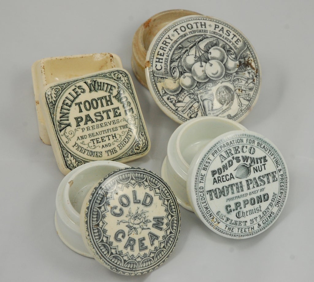 This collection of four antique ceramic pomade jars, three round, one square featuring period transfer decoration labeling the contents: Cold cream, cherry toothpaste, Ponds Areca nut toothpaste, and Vintelle's white rose toothpaste. They range in