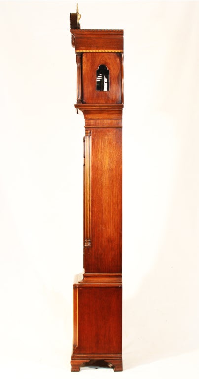 This fine antique American Federal style grandmother's long case clock features book matched crotch grain mahogany and walnut case with bracket feet, and a chamfered block base. The arch crest pendulum door features satinwood stringing and inlaid