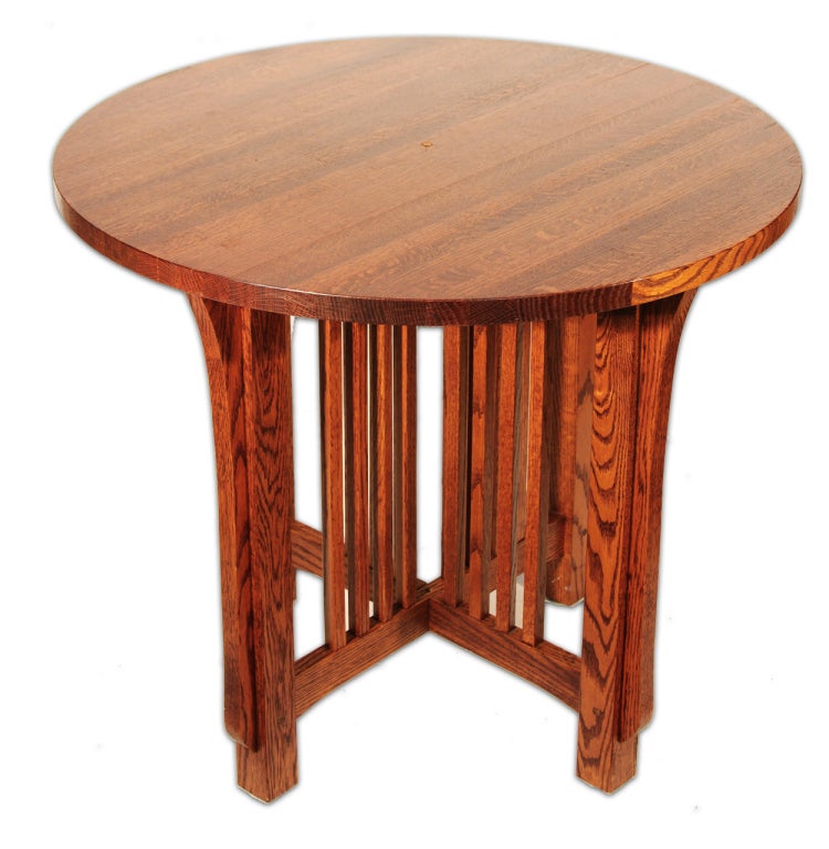 This pair of Arts & Crafts style lamp tables are composed of oak and given a cherry oak finish that brings out the depth of the wood. The circular tops have small holes for wiring the lamp cords. The bases feature intersecting trestles with square