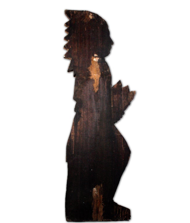 This bas relief wooden cigar store Indian sign has been caved into a single plank of poplar wood. It was then painted with a coat of gesso upon which dark brown red and ocher tones were applied. The Indian carries tobacco in his hand.  

Cigar
