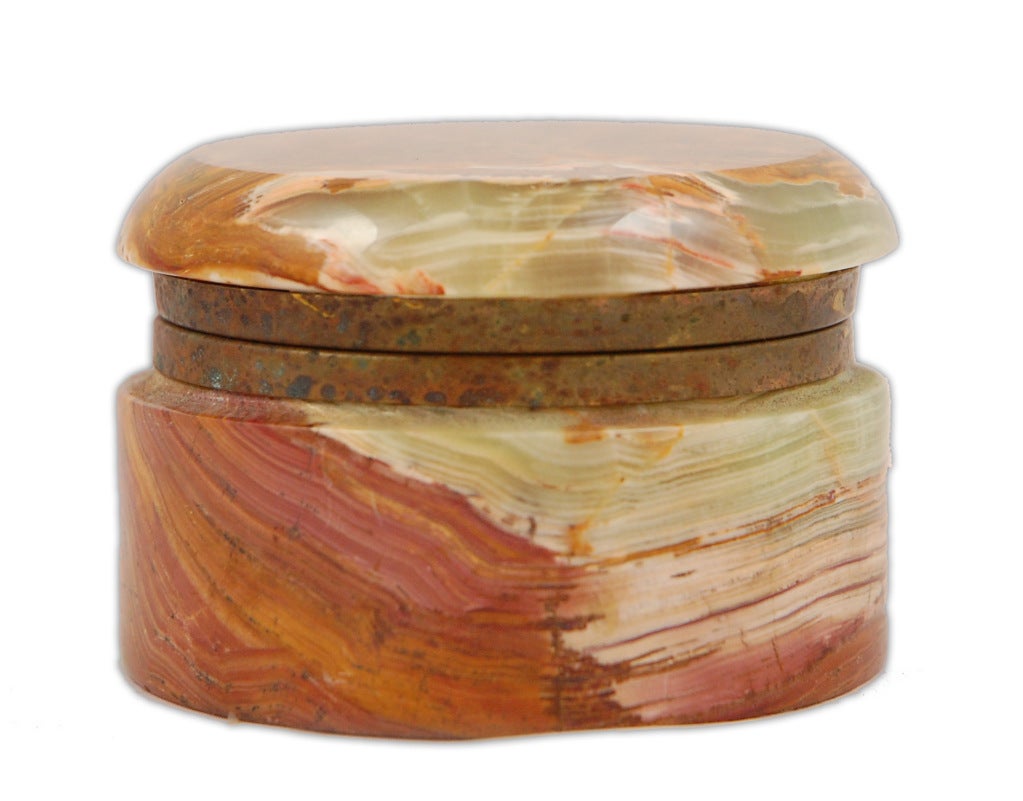 This Pakistan onyx marble lidded round box was most likely part of a boudoir set and intended to hold loose powder and a puff. The Pakistan onyx has marvellous veining in shades of coral, orange and green.