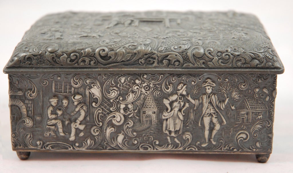 This Repousse Silver Plate box by Barbour S.P. International features intricately etched country village scenes with dancing figures and decorative scrolls on five surfaces in a rococo style.