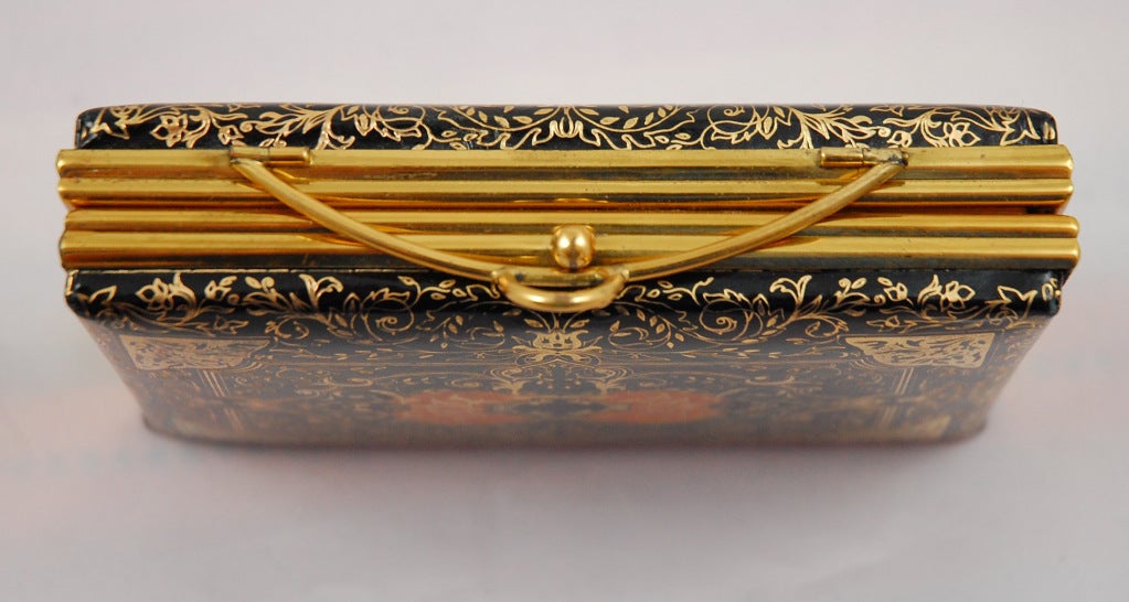 Italian tooled leather evening clutch with powder compact and mirror. The heavily gold stamped leather tooling is in an Italian Renaissance style motif with black, orange, green and gold. Interesting fold over metal clasp. The interior is