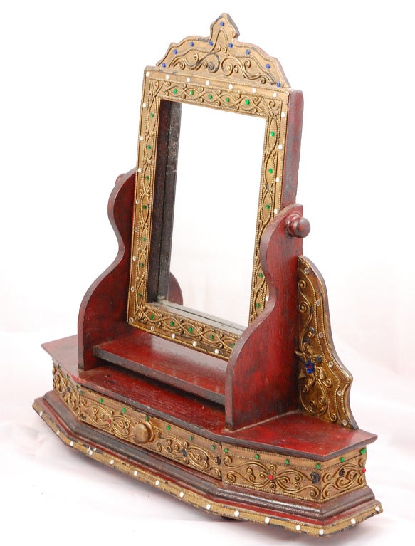 This beweled dressing mirror will make a wonderful addition to an eastern style room, with gold painted trim, jewels, and pressed tin, it is highly decorated and sits on four ball feet.