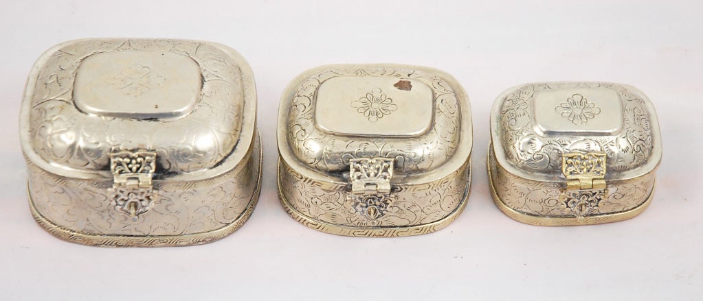This set of three silver plated nesting boxes are ornately stamped with geometric trim, scrolling hasp closures and folate stamping on bodies and lids. These are true nesting, they all fit into each other. Made in India.