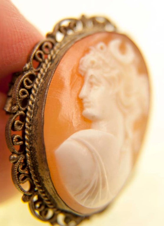 Beautiful hand-carved cameo with a left-facing profile of a young woman, set in a gold wire bezel and roped decorative framework.