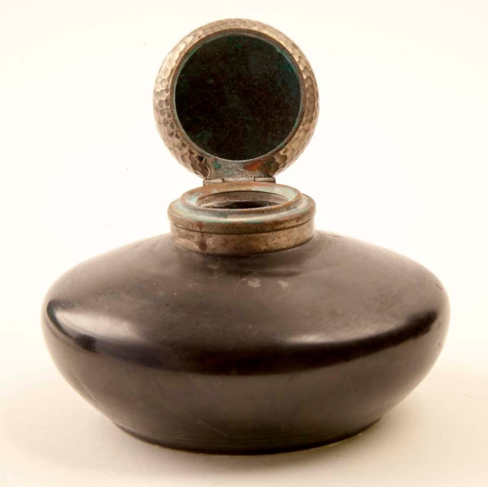 Glass inkwell with ball-peened silver flip cap. Blackened body with deco-clover pattern inside the glass.