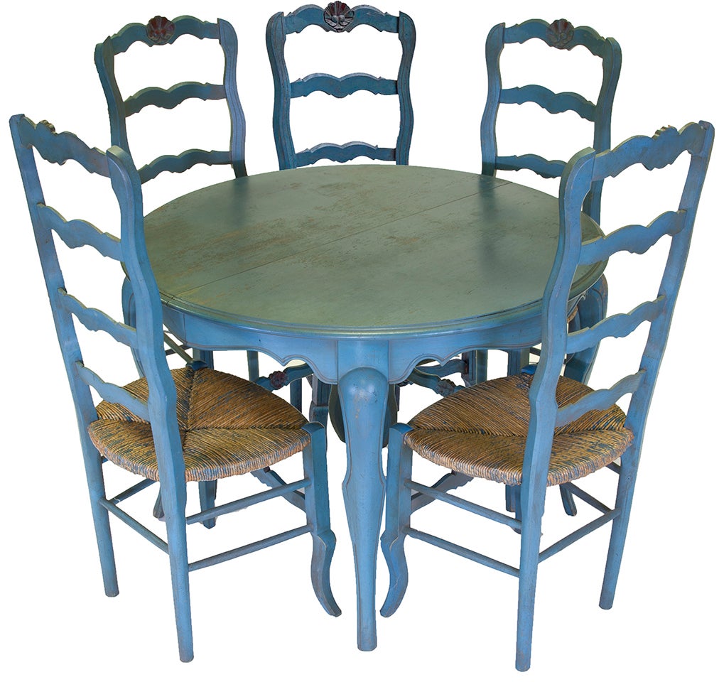 Beautiful grange French country provincial blue dining table and chairs includes hand-carved ladderback chairs with thin painted ruche, woven straw, seats and red toned sunflower motif at crowns. The table is a spring and coil operating design with