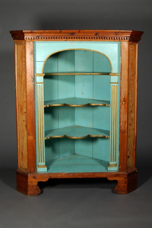 Charming French handmade and hand-painted corner cabinet on raw pine with blue and gold accents and dental molding.