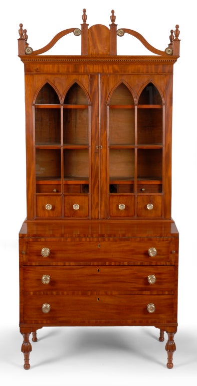 An intriguing Sheraton Mahogany Secretary Desk and Bookcase,  probably South central Maine, circa 1820. This attractive desk and bookcase has an exuberant gallery crest with bold reverse scrolled splats with pressed brass mounts.  The gallery is