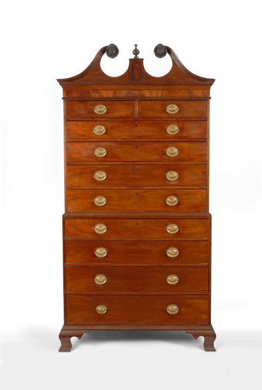 A handsome Federal mahogany chest-on-chest, the carvings attributed to Samuel F. McIntire,  Salem, Massachusetts, circa 1790.  This impressive chest-on-chest has an applied crest with molded broken arched scrolls terminating with finely carved