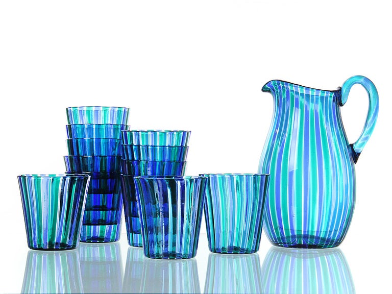 Purple, blue, and green striped on blue hand-blown glass. Twelve (12) glass tumblers and one pitcher. The glasses are unmarked. The carafe carries the acid etched mark used by Venini between 1947 and 1966.