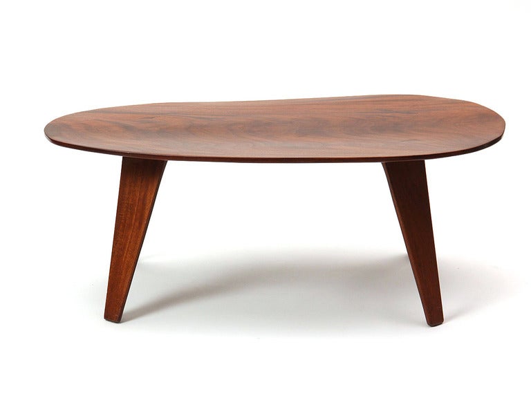 An asymmetrical solid walnut low table on splayed and tapered legs. Marked 