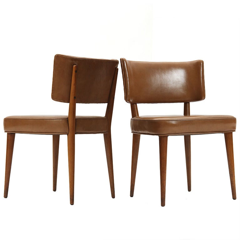 An elegant game or dining chair with a curved back and generous seat atop walnut tapered dowel legs, with rear legs that continue up to support the back.
 