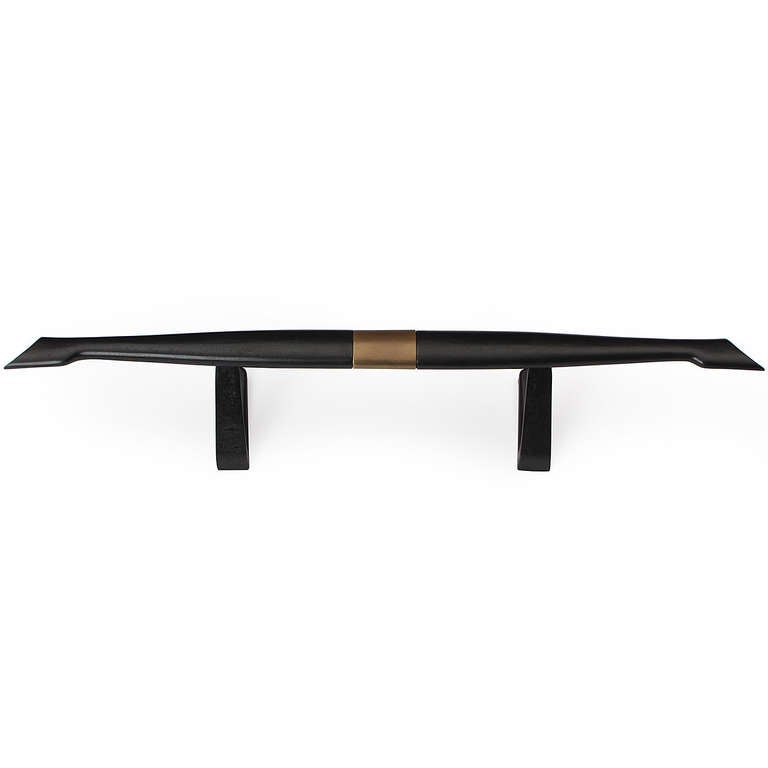 A sculptural fire guard in iron and brass having a flaring tapered form, floating on two angled legs.