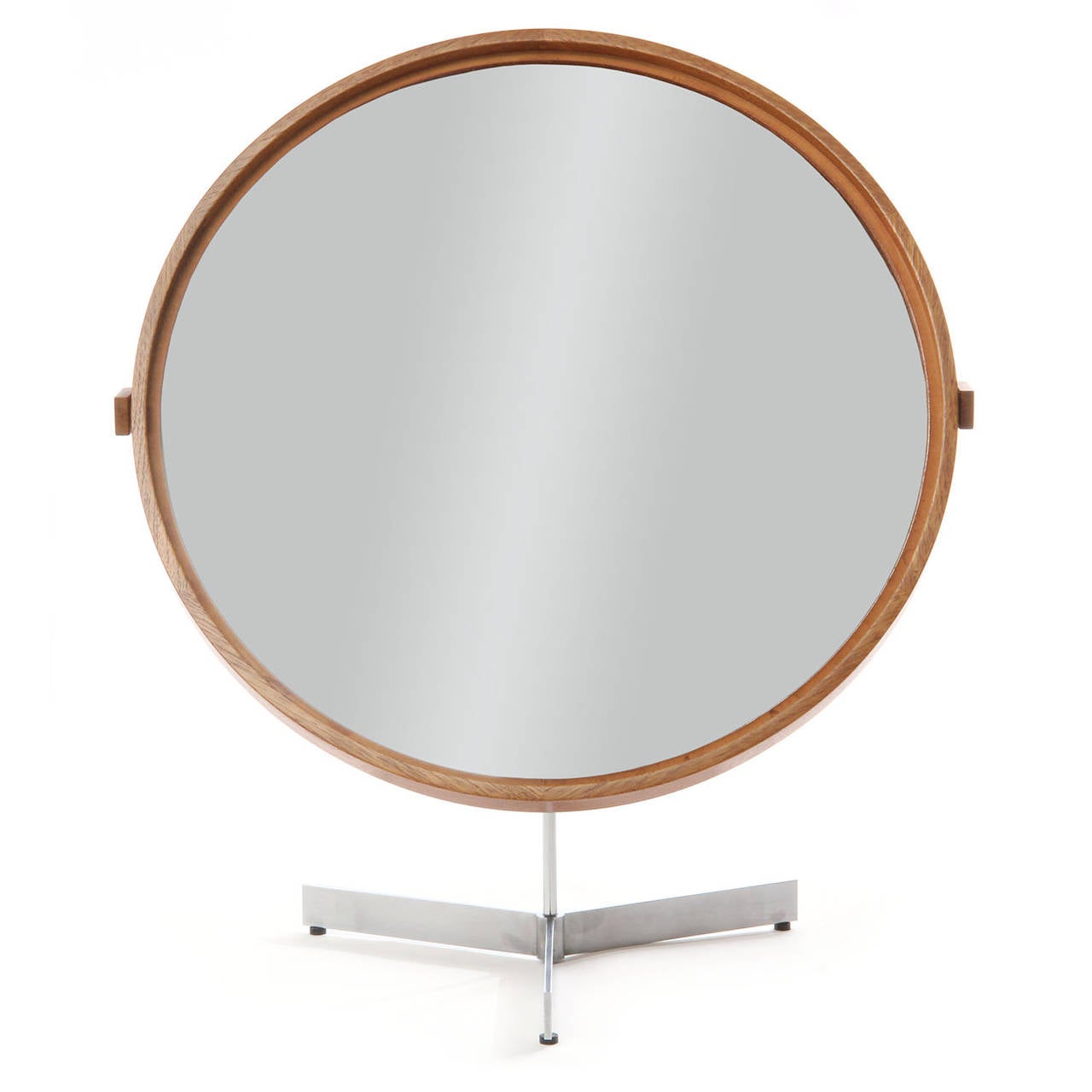 A sculptural and elegant tilting and swiveling oak framed vanity mirror that floats on a spare architectural brushed steel tripod base.